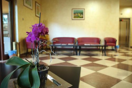a vase with purple flowers on a table in a waiting room at Hotel Ruffirio in Vinchiaturo