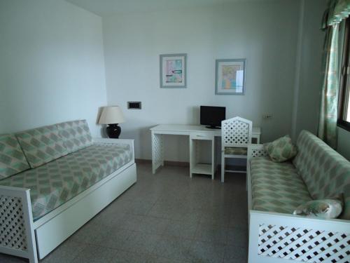 a living room with a couch and a desk with a computer at Hotel las Conchas in La Rábita