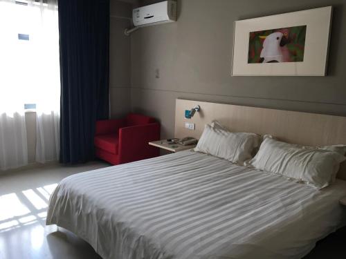 a hotel room with a bed and a red chair at Jinjiang Inn Lijiang Ancient City Qixing Street in Lijiang