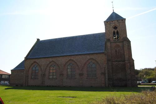 eine große Backsteinkirche mit einem Uhrturm in der Unterkunft Het Verschil in Zoutelande
