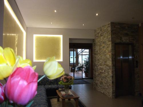 a living room with a couch and a table with flowers at Hotel alle Rose in Cavedago
