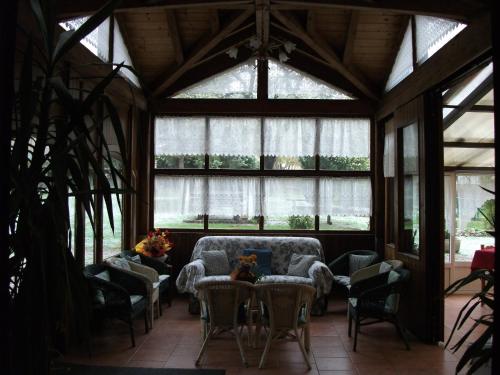 a living room with a couch and chairs and windows at Hotel alle Rose in Cavedago