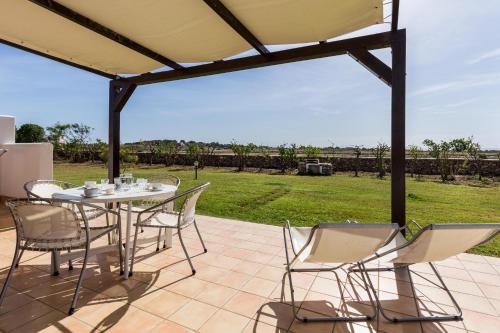 a patio with a table and chairs and a field at Le Casette a Favignana in Favignana
