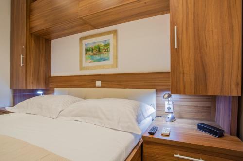 a bedroom with a white bed with a wooden headboard at Apartments Calma in Cres