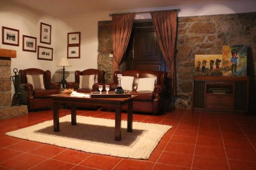 a living room with a table and leather chairs at Casa Dona Urraca in Vilarinho da Castanheira