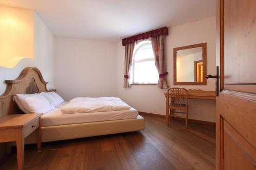a bedroom with a bed and a table and a mirror at Hotel Fanes Suite & Spa in Moena