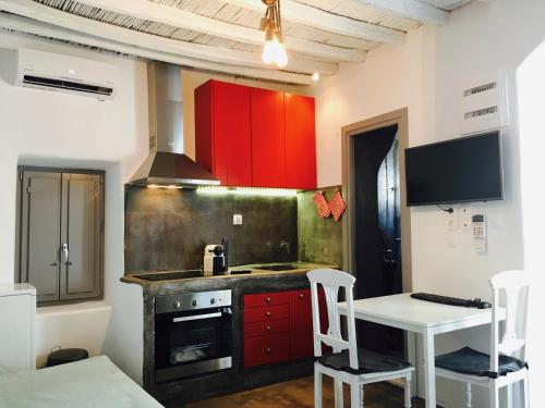 una cocina con armarios rojos y una mesa y sillas blancas. en Naoussa Center Home en Náousa