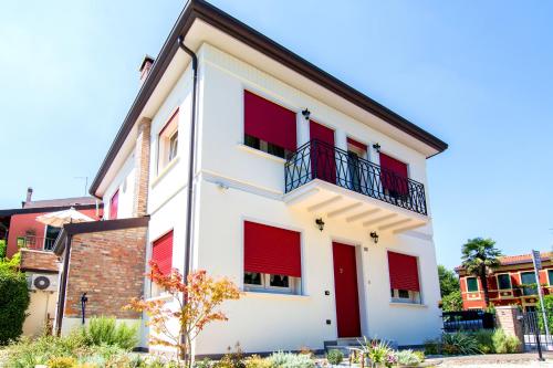 a white building with red shutters on it at B&B La Porta Rossa in Noale