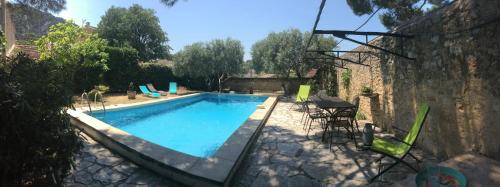 una piscina en un patio con mesa y sillas en Maison Daumas Billard Français et Piscine en Robion en Luberon
