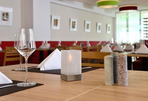 a wooden table with a glass of wine on it at Aribo Hotel in Erbendorf