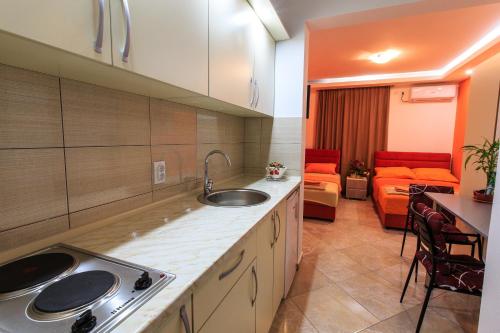 a kitchen with a sink and a living room at De Lux Apartments Luka in Bar