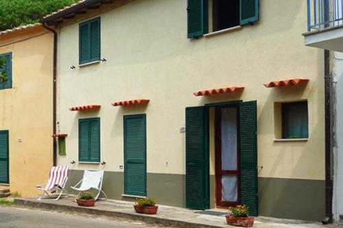 two chairs sitting outside of a building with green shutters at Casa Pineta in Procchio