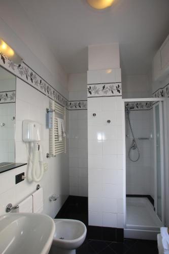 a white bathroom with a shower and a sink at Hotel Elena in Recco