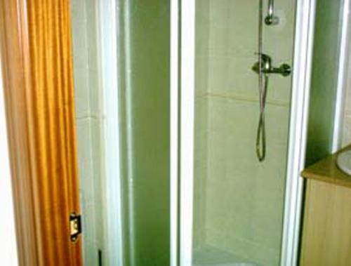baño con ducha y puerta de cristal en Hostal Las Sabinas, en Bujaraloz