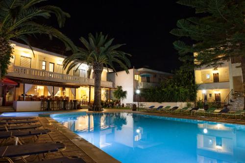 a swimming pool at night with chairs and a hotel at Cretan Sun in Platanes