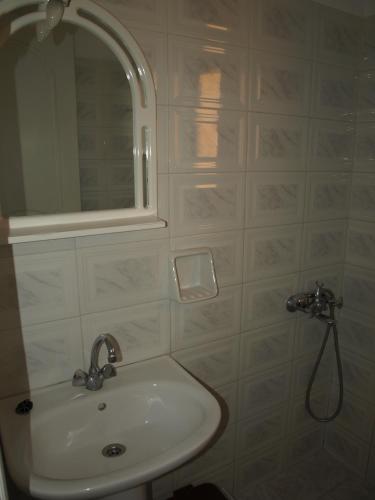 a white bathroom with a sink and a mirror at Studios Vagos 2 in Agios Prokopios