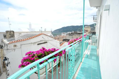 a balcony with pink flowers on a white building at Merydamy in Mattinata