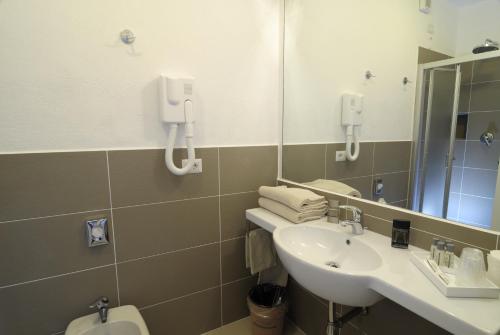 a bathroom with a sink and a mirror and a toilet at Hotel Ambrosio La Corte in Olbia