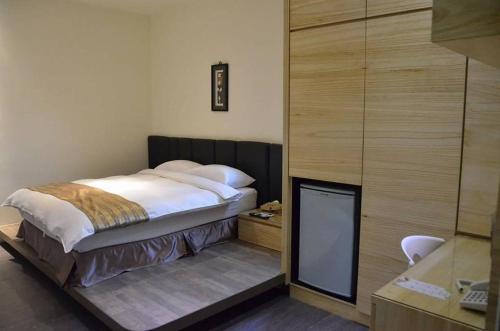 a bedroom with a bed and a desk with a phone at Happy Hotel in Lukang