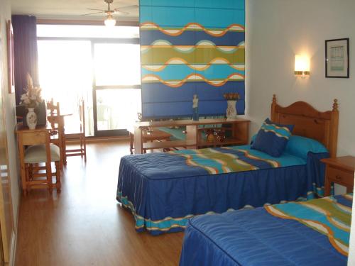 a bedroom with two beds and a table and chairs at Fenix Apartamentos in Roquetas de Mar