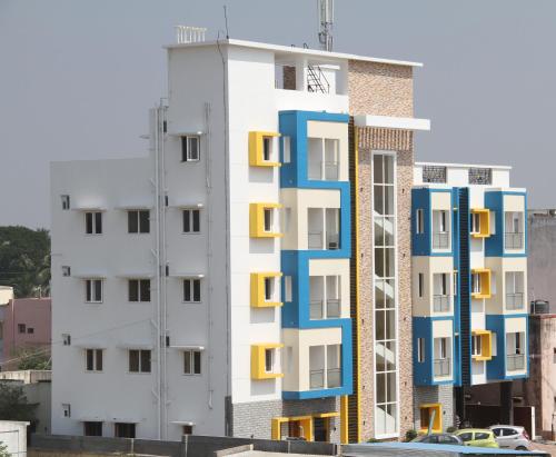 a tall white building with blue and yellow windows at Jeyam Residency in Dindigul