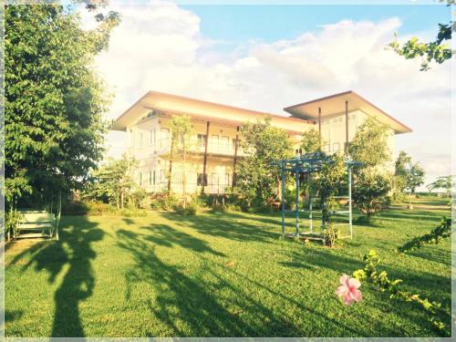 un gran edificio con un parque infantil en el patio en Thorfun Guesthouse in the Garden, en Nakhon Ratchasima