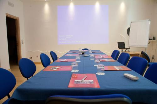 a long table in a room with blue chairs and a screen at Hotel d'Altavilla in Canosa di Puglia