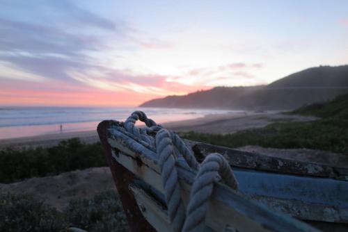 a bench on a beach with the sunset in the background at Ti’amo in Wilderness