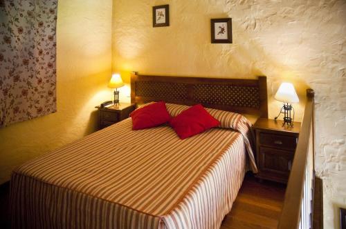 1 dormitorio con 1 cama con 2 almohadas rojas en Hotel Galaroza Sierra en Galaroza