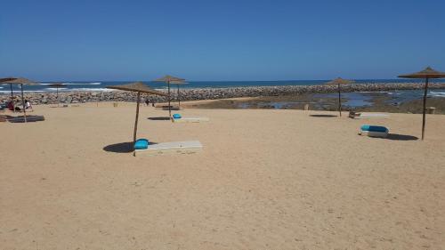 a beach with umbrellas and chairs on the sand at Bahia Golf Beach Apartement in Bouznika