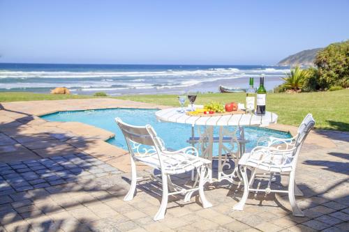 a table and chairs next to a pool with a bottle of wine at Ti’amo in Wilderness