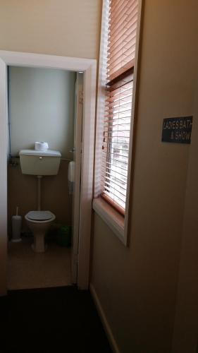 a small bathroom with a toilet and a window at Railway Hotel Greymouth in Greymouth