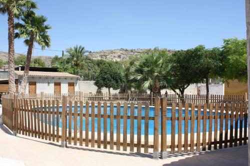 einen Holzzaun neben einem Pool mit Palmen in der Unterkunft Rural Romana in La Romana