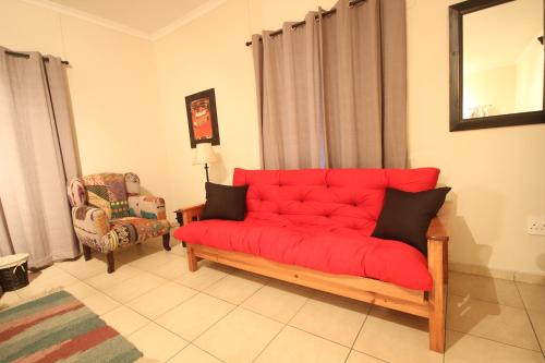 a red couch in a living room with a chair at Eazy Sleep Accommodation in Swakopmund
