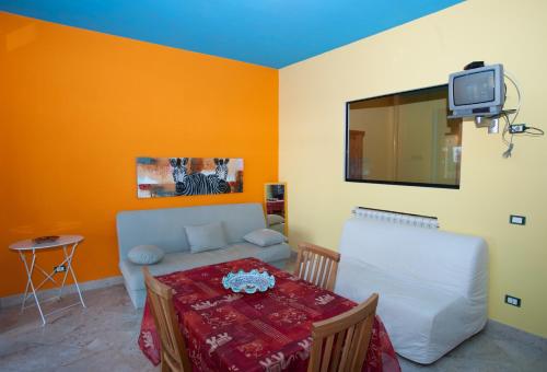 sala de estar con mesa, sofá y TV en Azzurra Cielomare, en Castellammare del Golfo