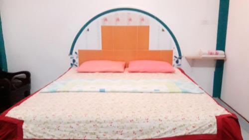 a bed with two pink pillows in a bedroom at Jidapha Rooms in Khlong Thom