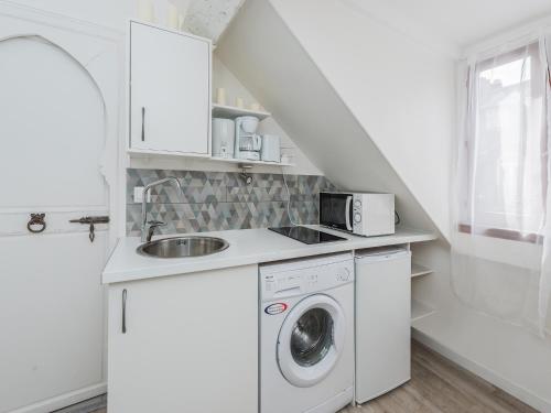 - une cuisine blanche avec un lave-linge et un évier dans l'établissement Appartement satory, à Versailles