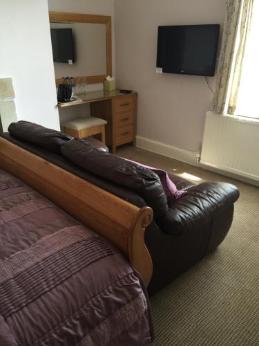 a couch in a hotel room with a television at Sandpiper House in Whitby