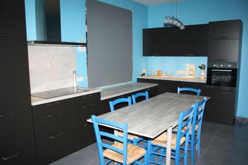 a kitchen with a wooden table and blue chairs at Gite Au Cortil in Chevetogne
