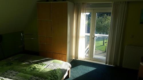 Schlafzimmer mit einem Bett und einer Glasschiebetür in der Unterkunft B&B de Kornelishoeve in Drouwen