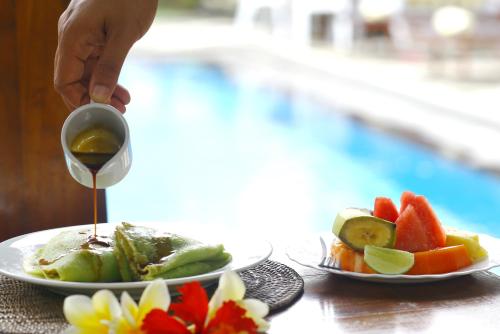 uma pessoa servindo vinho em dois pratos de frutas em Sagitarius Inn em Ubud