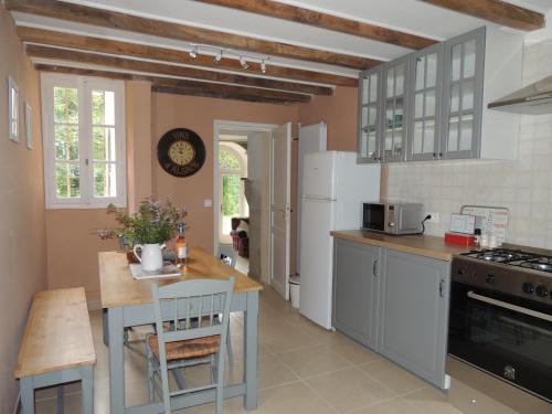 une cuisine avec des appareils électroménagers blancs, une table et un comptoir dans l'établissement La Tour du Chambon, à Brignac-la-Plaine