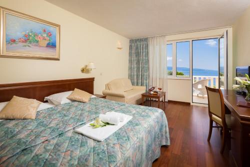 a hotel room with a bed with a table and a balcony at Hotel Villa Bacchus in Baška Voda