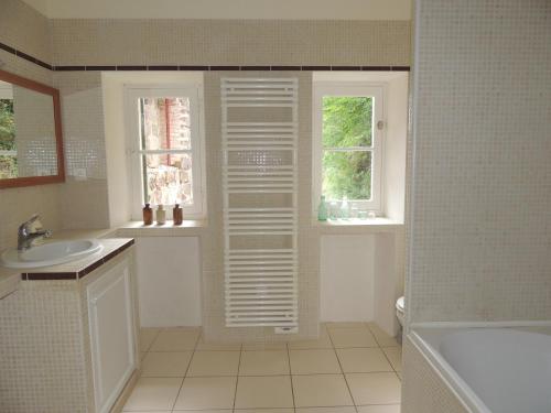 La salle de bains est pourvue d'un lavabo, d'une baignoire et d'une fenêtre. dans l'établissement La Tour du Chambon, à Brignac-la-Plaine