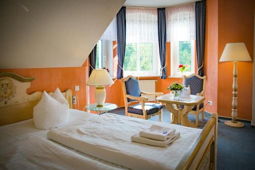 a hotel room with a bed and a table and chairs at Hotel & Restaurant Waldschlösschen in Kyritz