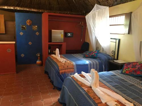 a hotel room with three beds and a television at The Pickled Onion Eco-Boutique B&B in Santa Elena