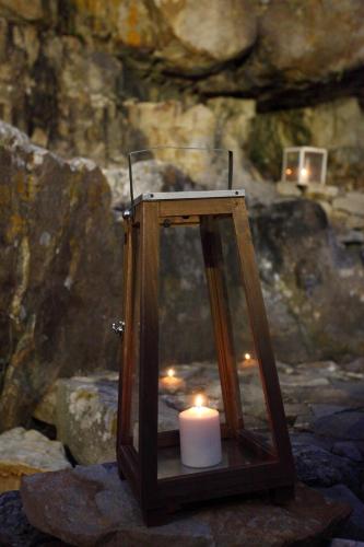 a candle in a wooden lantern on some rocks at jusu e susu montagna mare in Mistretta