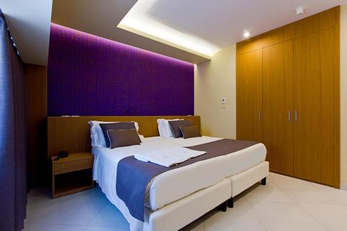 a bedroom with a large bed with a purple wall at DubaiVillage in Camposano