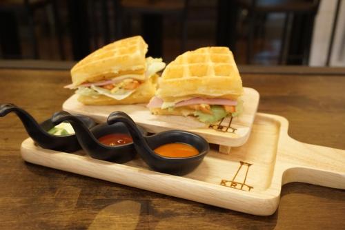 een doormidden gesneden sandwich op een houten dienblad met saus bij Krit Hostel in Bangkok