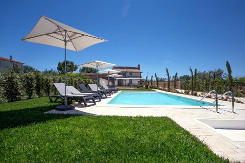 a pool with chairs and an umbrella next to a house at Casale905 in Crecchio